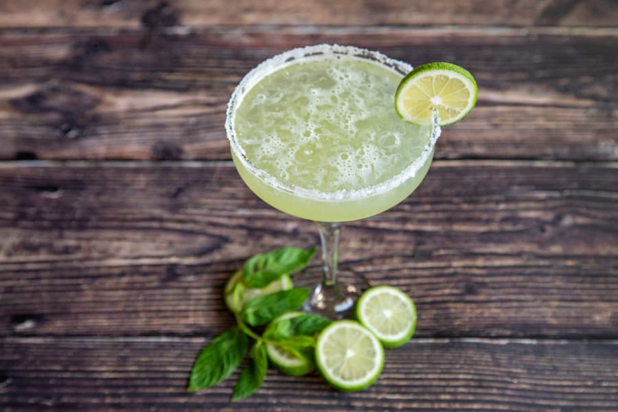 Margarita cocktail with lime wheels and mint