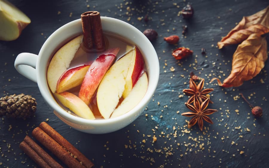 Apple cider surrounded by whole spices
