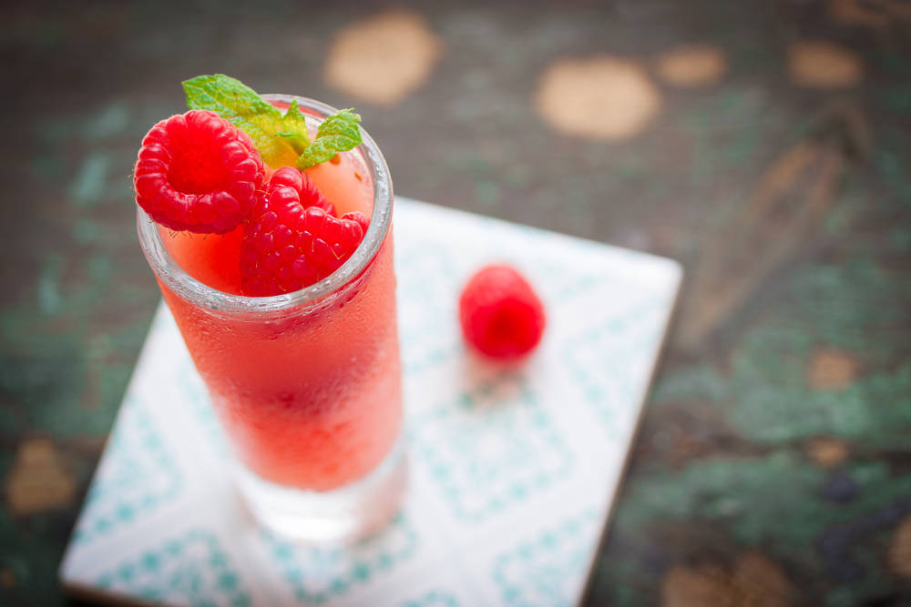 Homemade summer cold raspberry beverage with crushed iced and raspberries.