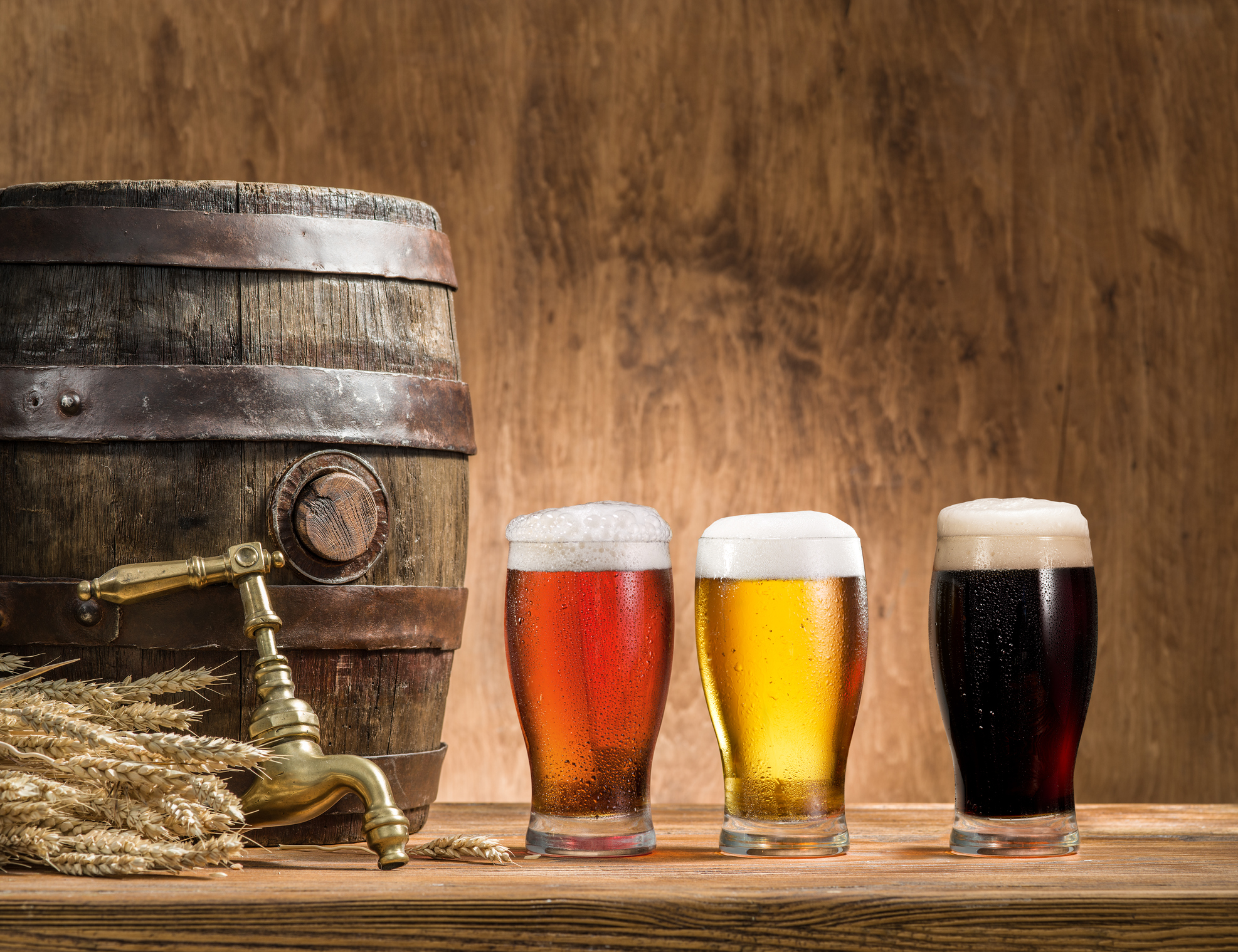 Glasses of beer and ale barrel on the wooden table. Craft brewery.