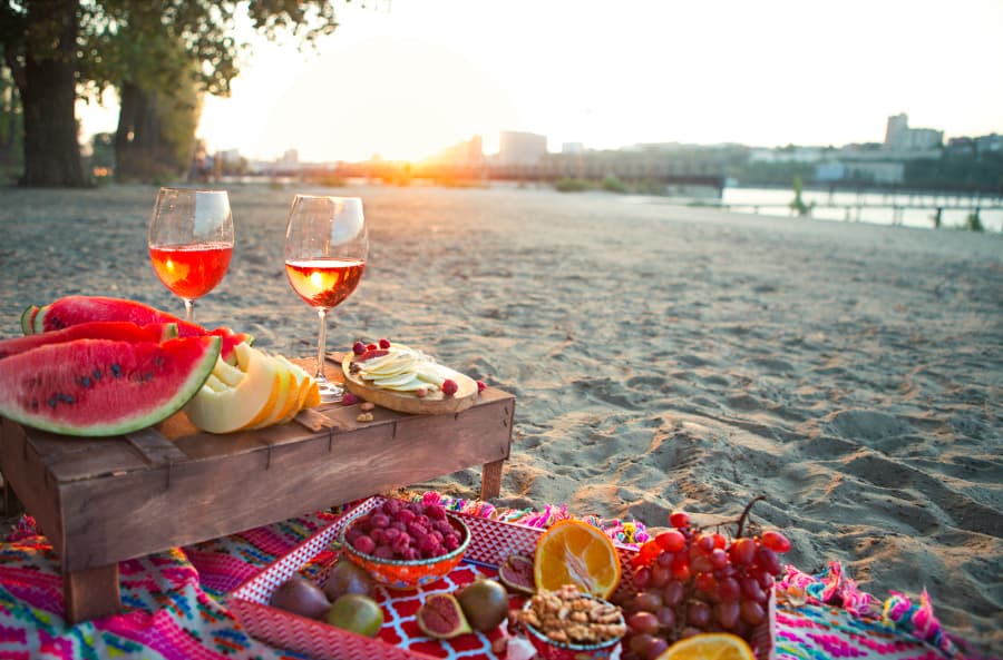 Selection of fruit and healthy snacks with wine picnic on beach