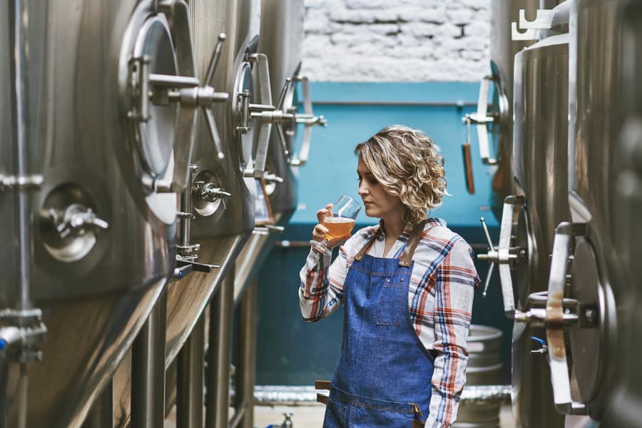 Woman Examining Beer Sample In Brewery