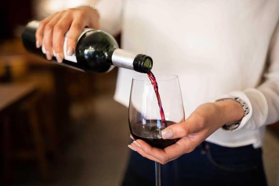 Woman pouring wine into stemless glass