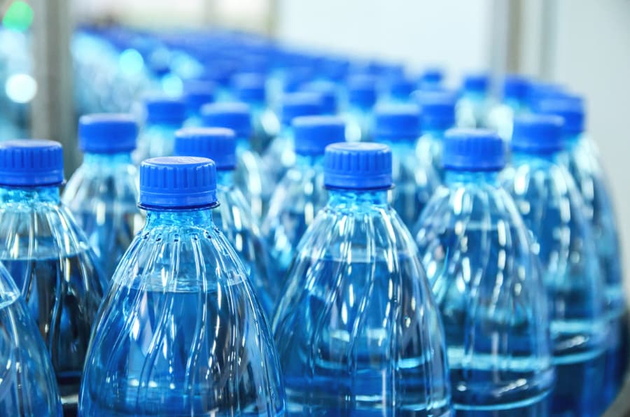Bottles of mineral water with blue caps on an assembly line