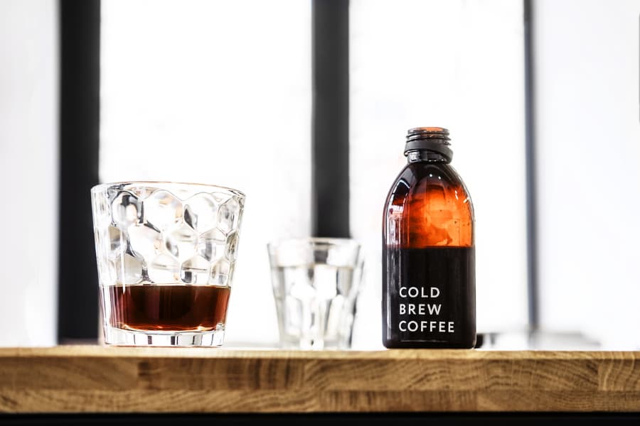 Bottle of cold brew coffee and two glasses on wooden tabletop