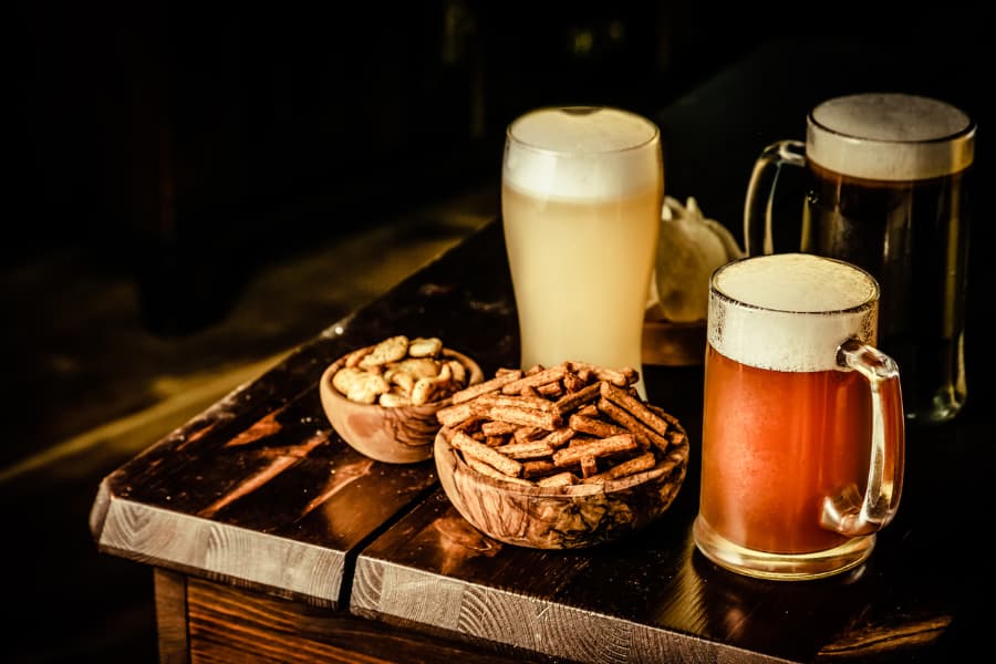 Two glasses of beer on wooden table surrounded by autumn yellow leaves