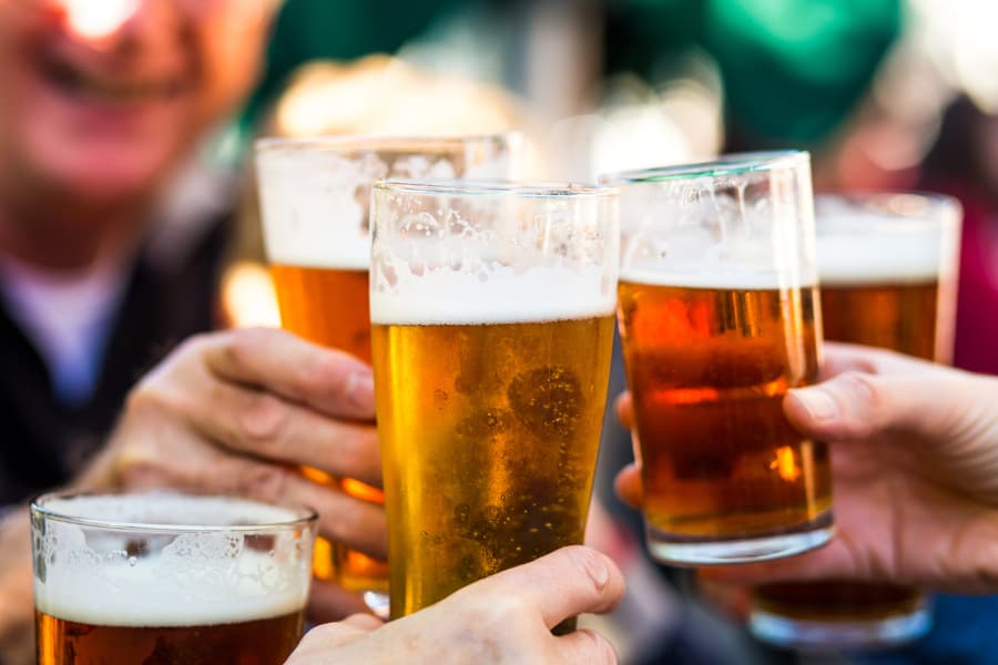 Closeup of pints of beers being toasted by group of people 