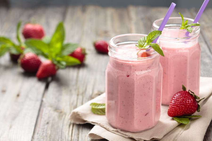 Tequila Rose milkshakes in jars with straws and fresh strawberries