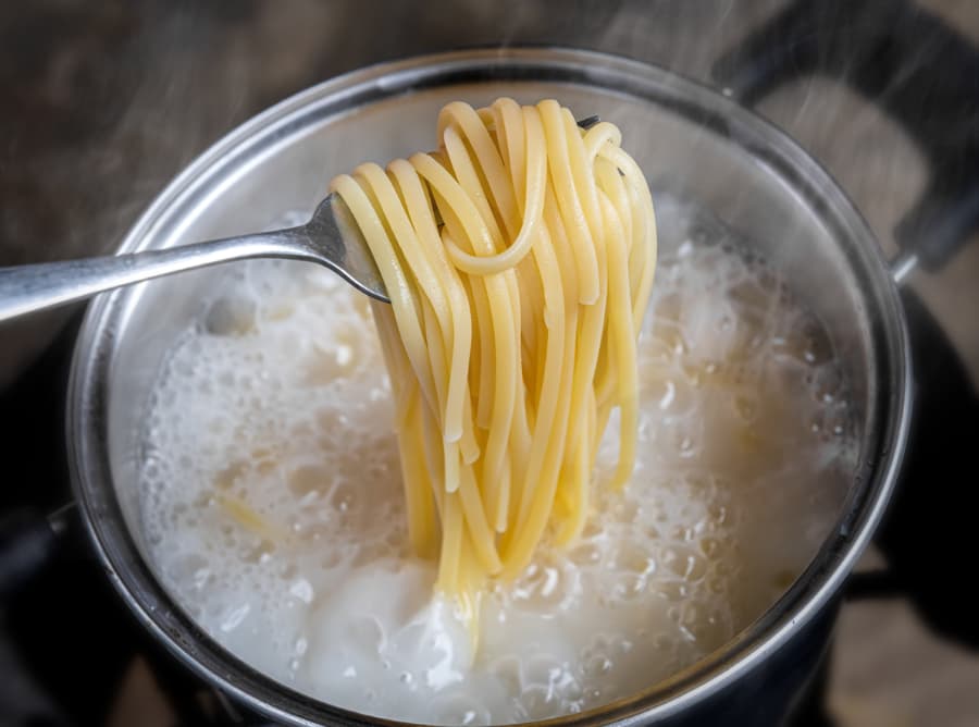 Spaghetti noodles in boiling water pot