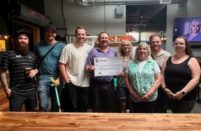 Columbia Distributing employees pose with giant check representing donation to help animals